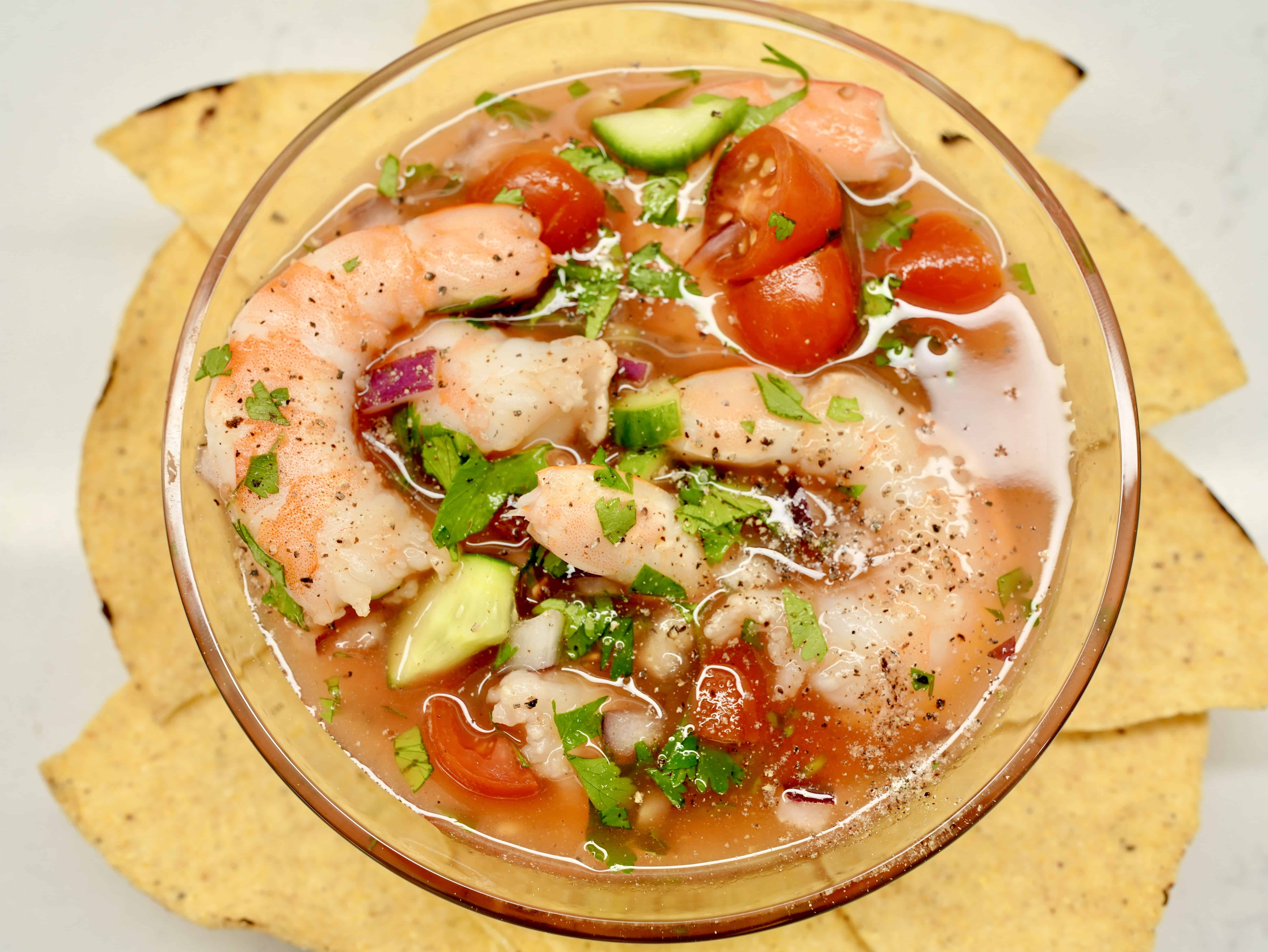 Shrimp cocktail served in a glass with pieces of tostada wrapped around the glass