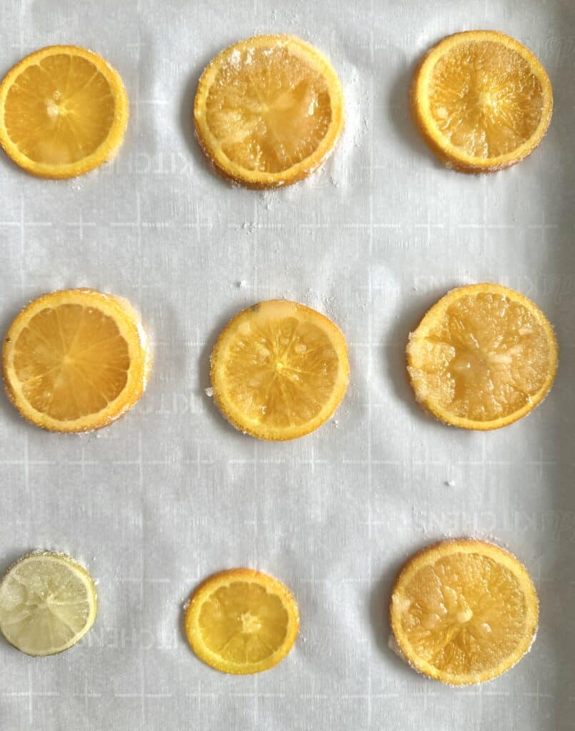 Sliced oranges on baking sheet coated in sugar