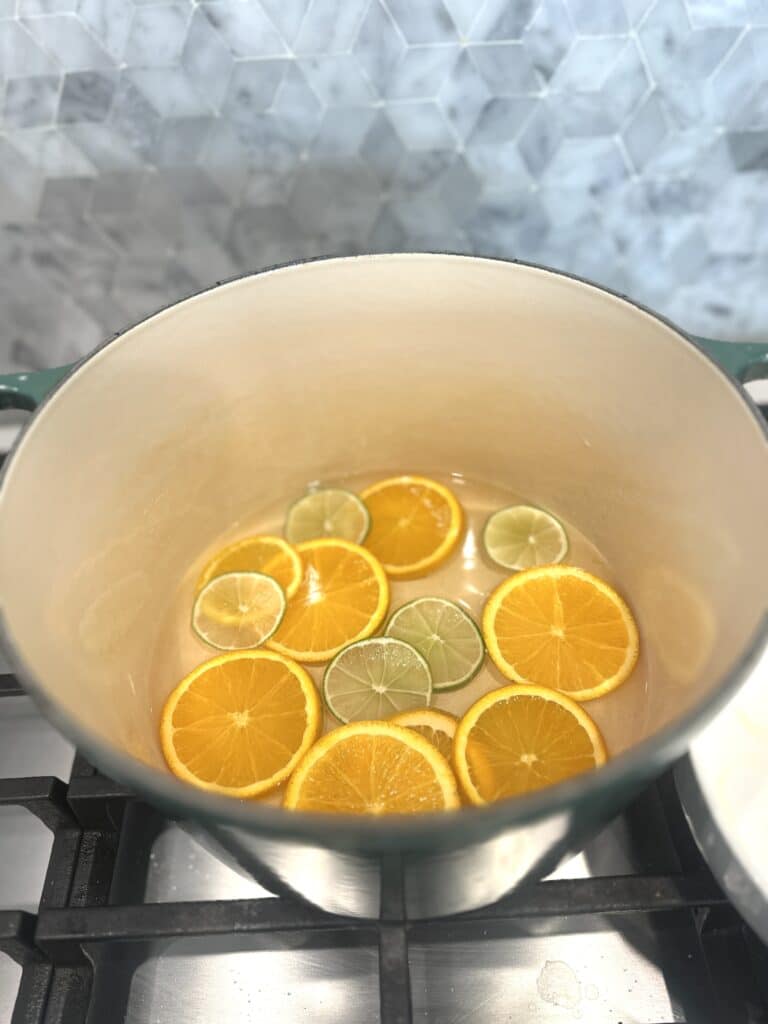 Sliced citrus oranges and limes in green dutch oven pot on stove