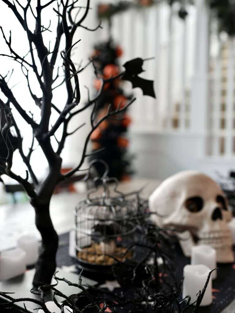 Halloween decorated table with black tree, birdcage and skull as the centerpiece